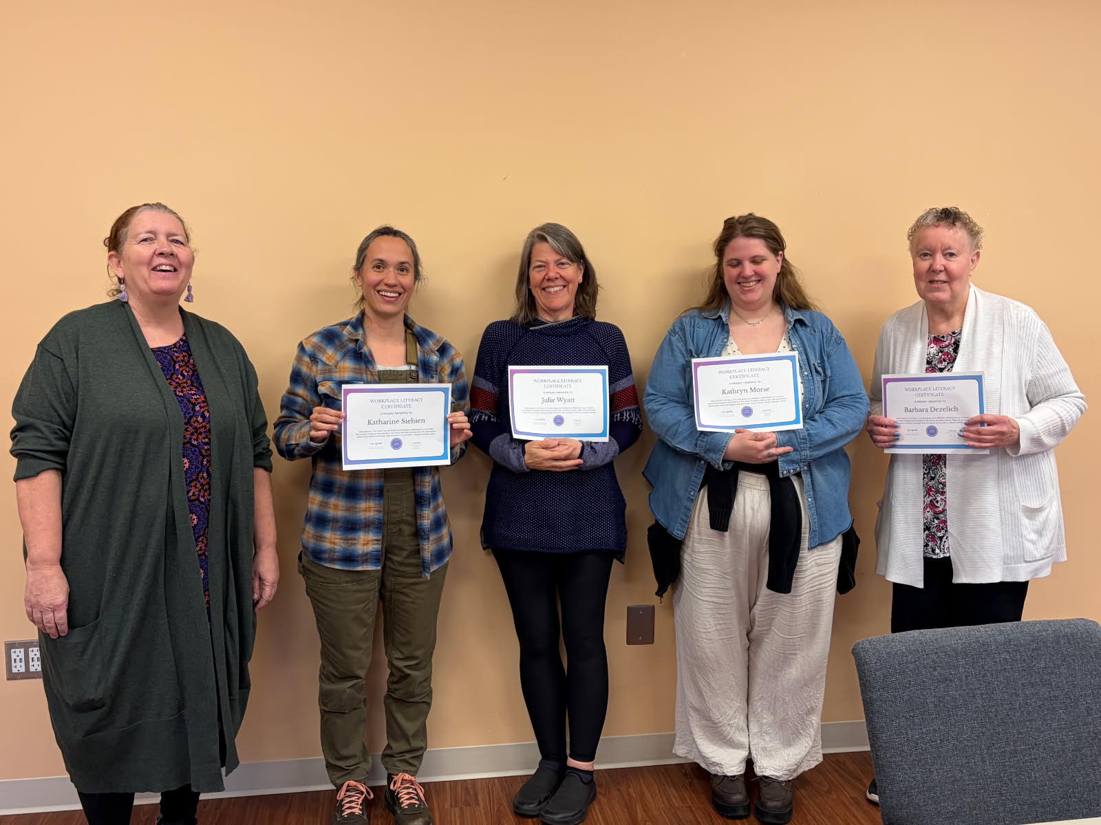 photograph of five smiling women, four holding certificates