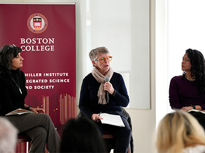 Three women participating in a panel discussion in front of an audience.