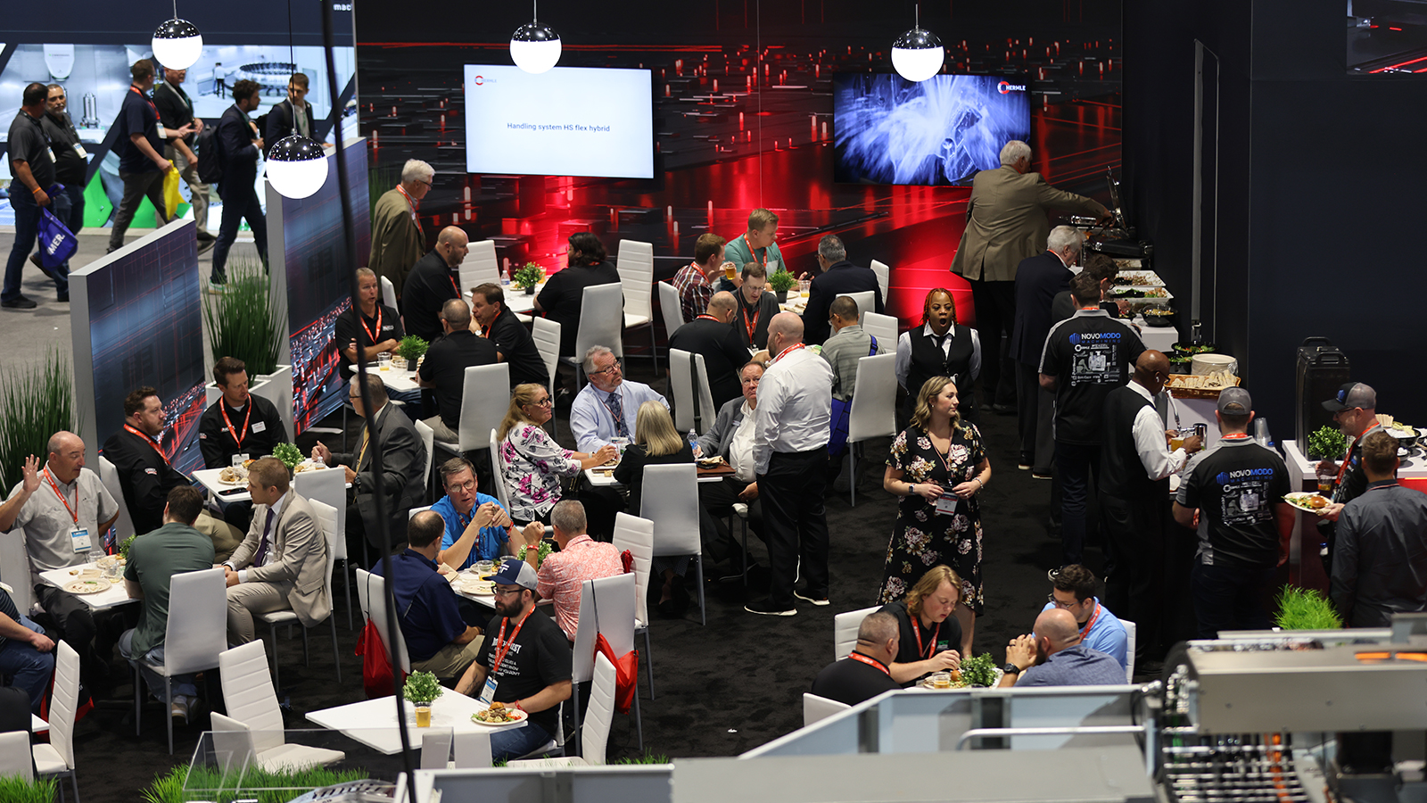 Attendees dining at HERMLE booth lounge