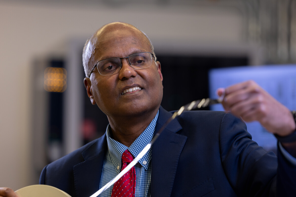 Male professor wearing a blue jacket and red tie holding superconductivity tape