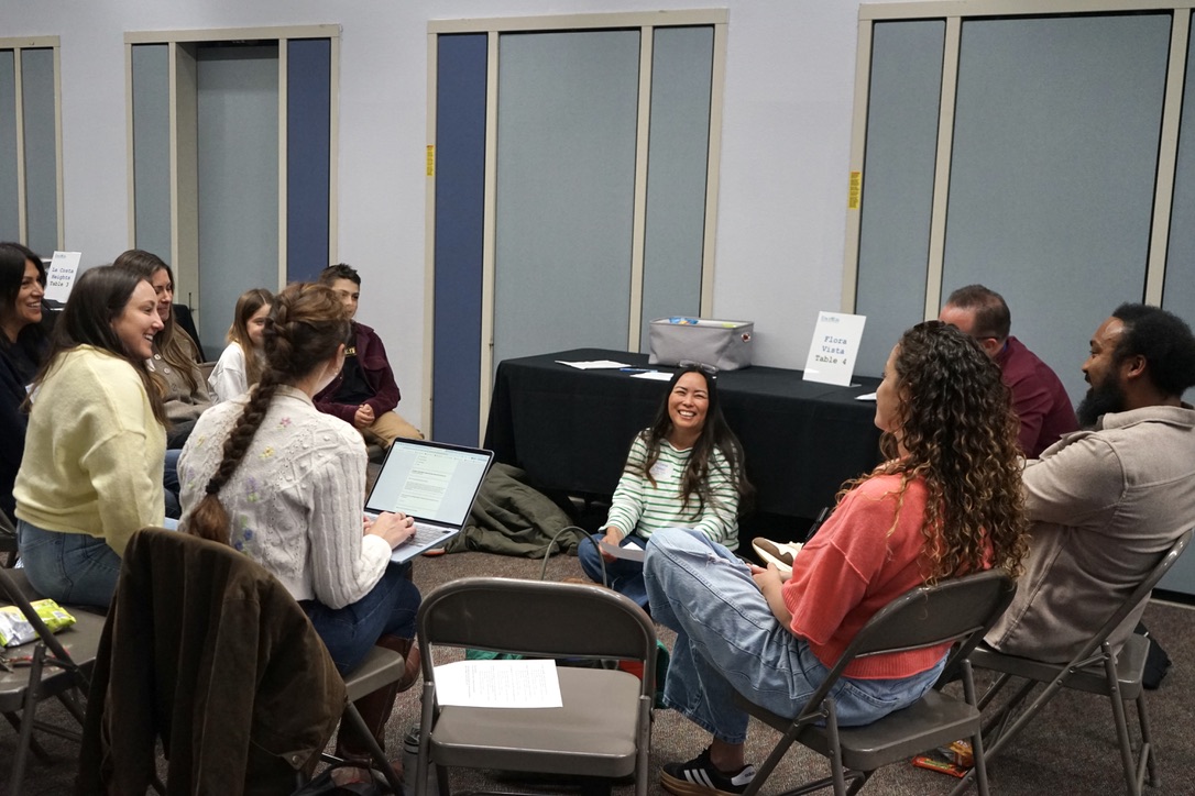 Adults and students sit in a circle having a discussion