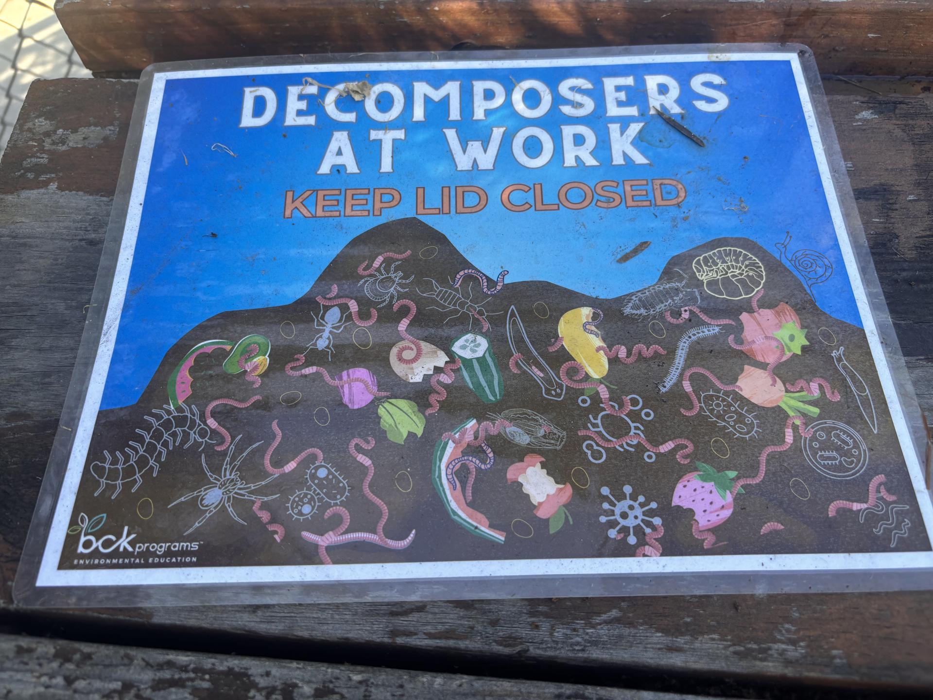 A poster that says Decomposers at Work, Keep Lid Closed, that shows an animated image of worms and bugs in a pile of dirt.