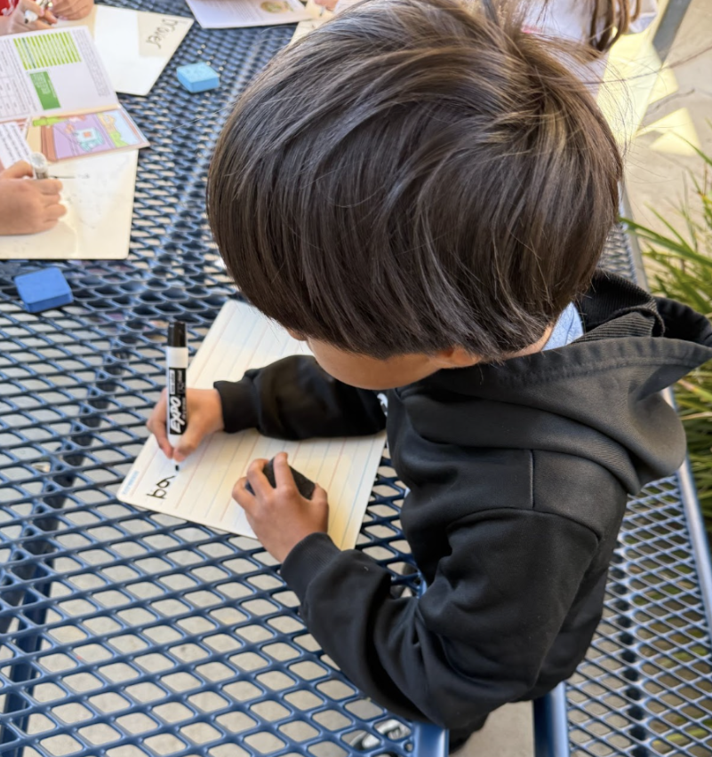 Student practices writing on a small white board