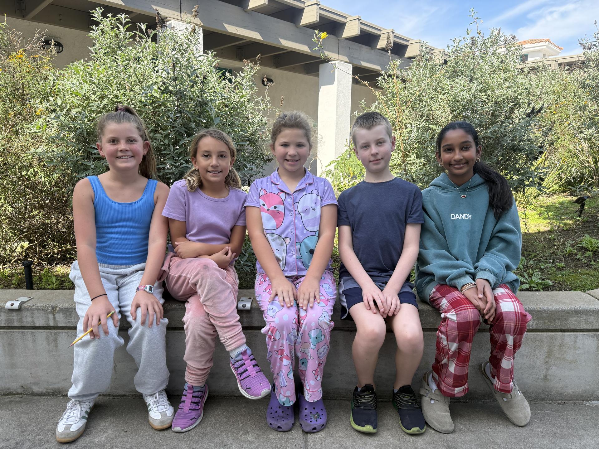 Five student tour guides sit for a photo, smiling.