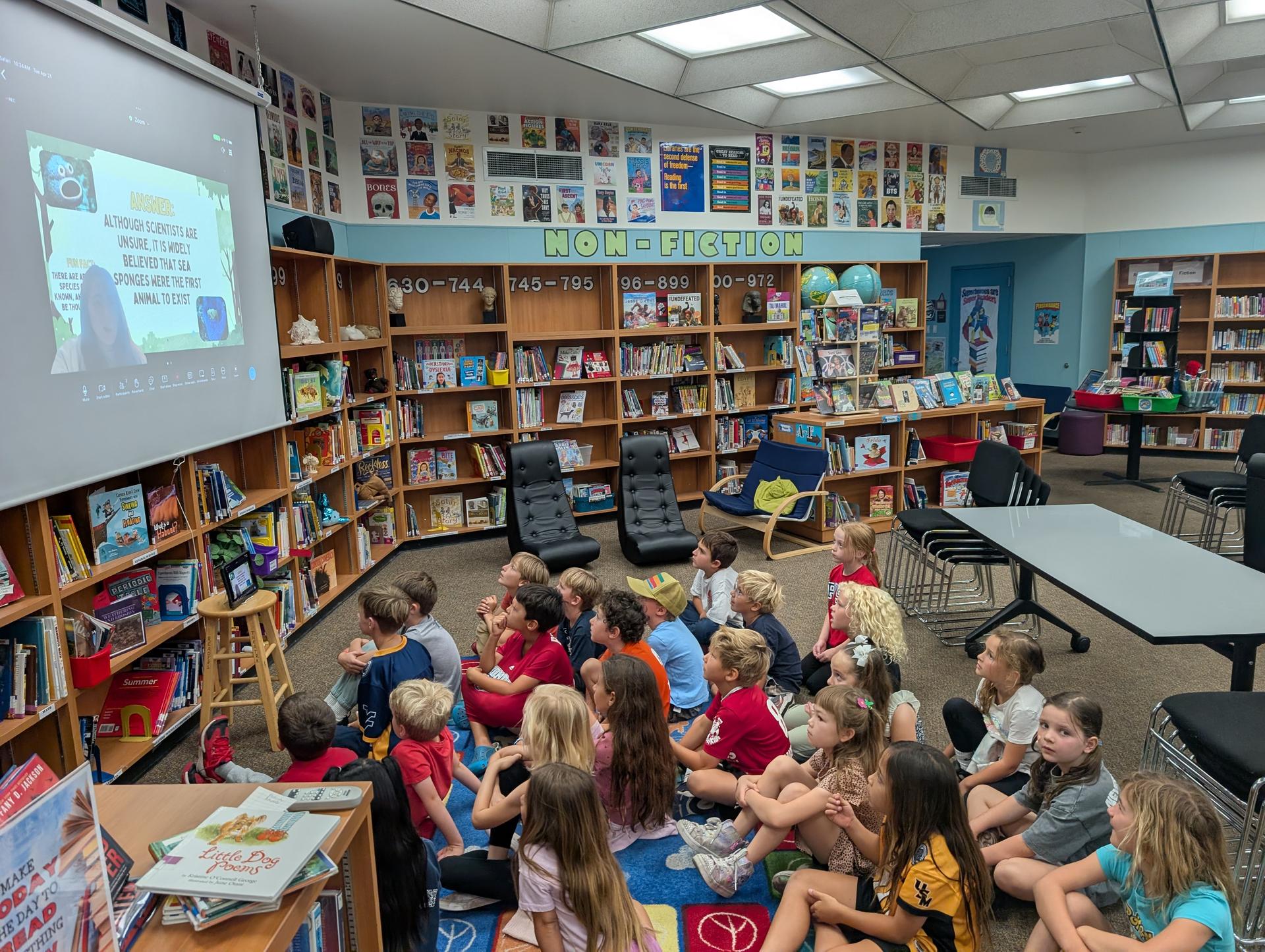 Students sit in the library watching a presentation