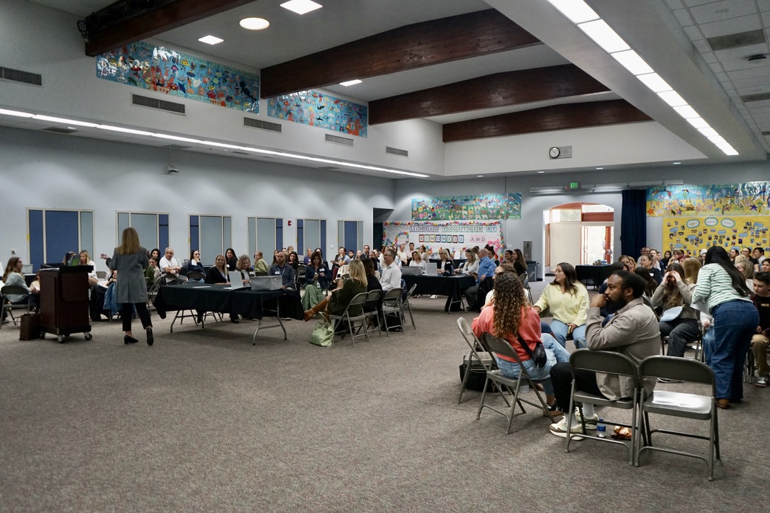 100 people sit in the audience as Dr. Grey welcomes everyone to the event.