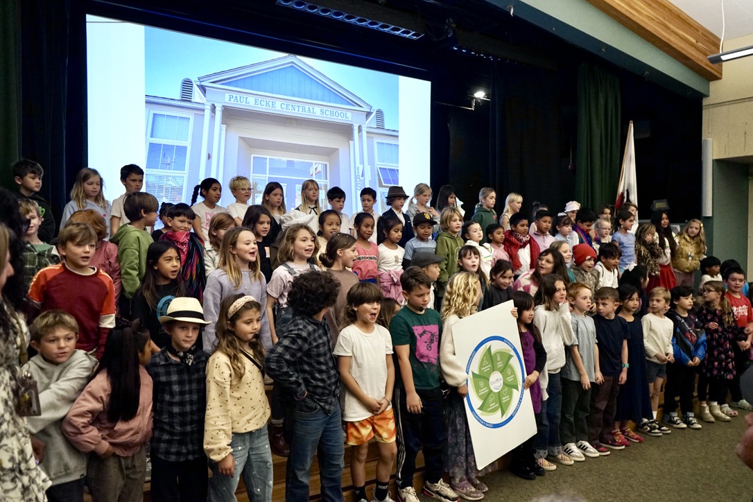More than 60 second grades students stand on the stage after their presentation is finished