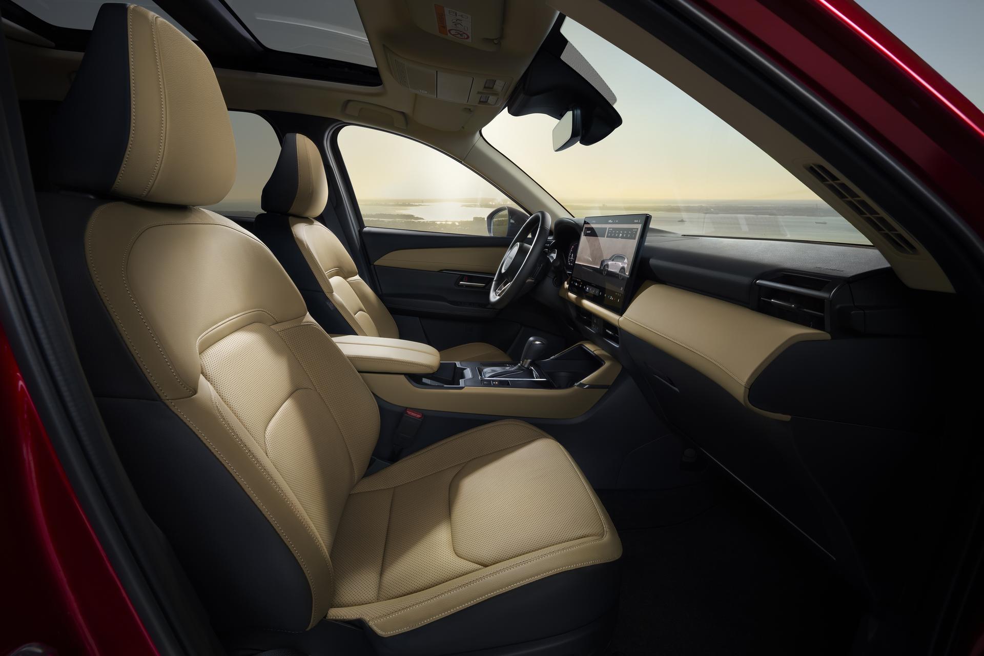 Driver-focused CX-5 cockpit with tan leather seating, center display, and panoramic moonroof overlooking a scenic waterfront. Driver-focused CX-5 cockpit with tan leather seating, center display, and panoramic moonroof overlooking a scenic waterfront.