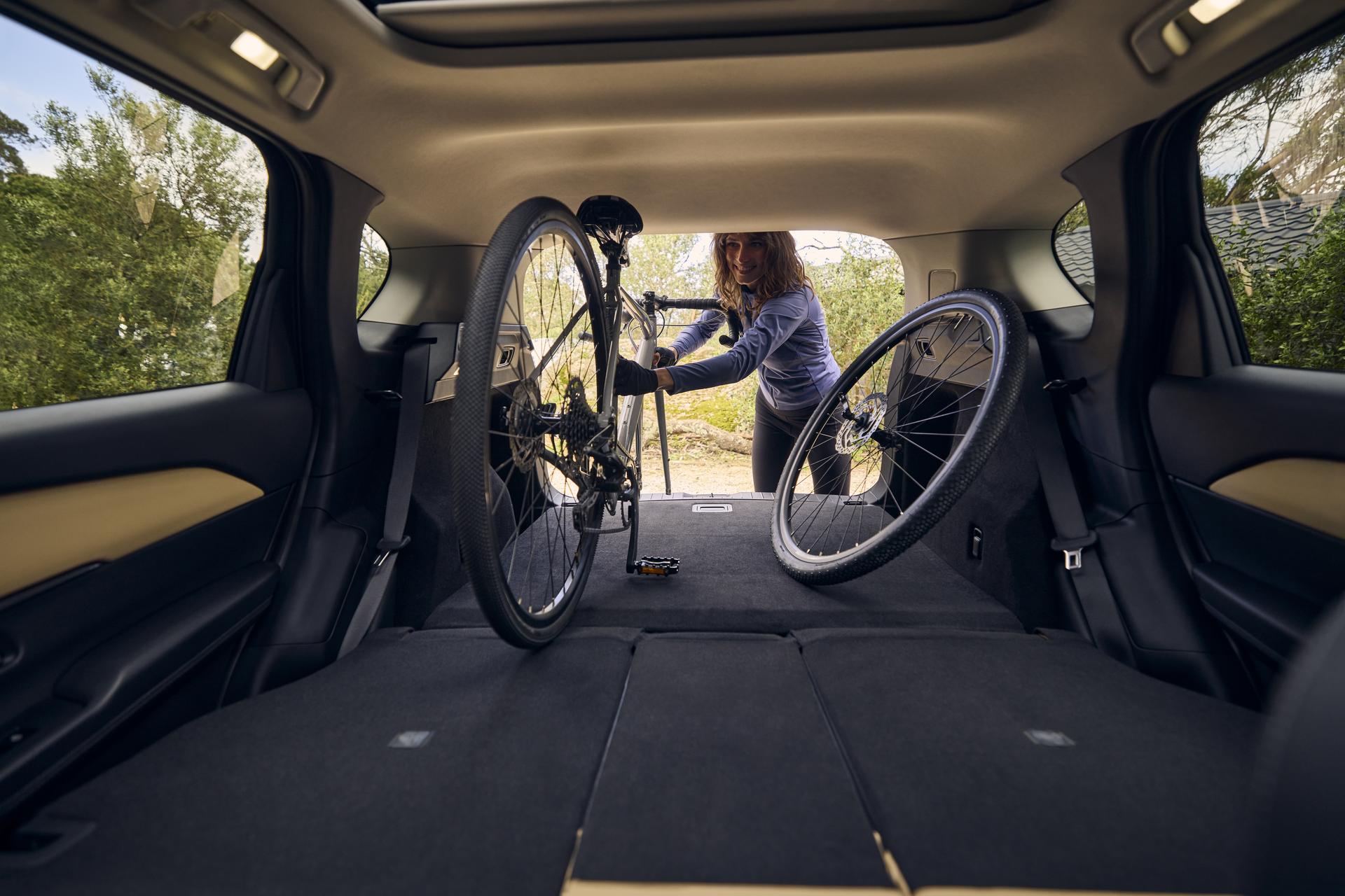 CX-5 cargo area with rear seats folded flat, demonstrating expanded storage space while loading a bicycle. CX-5 cargo area with rear seats folded flat, demonstrating expanded storage space while loading a bicycle.