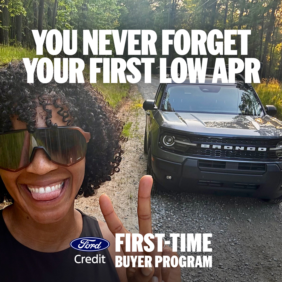 Person smiling beside a Ford Bronco on a wooded trail, with text promoting the Ford Credit First Time Buyer Program.