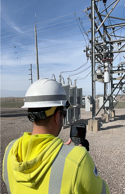 Watching lineman from the back inspect substation 