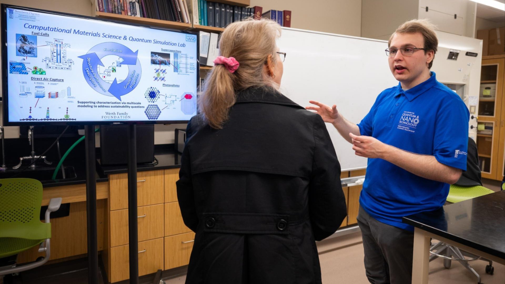 Photo of Julian Rus discussing his poster with an attendee of the QNTRibbon Cutting