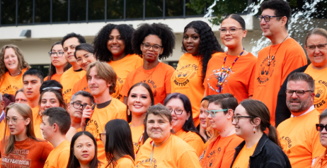 Students take a group photo in front of the fountain. All individuals are wearing an orange shirt to show support.