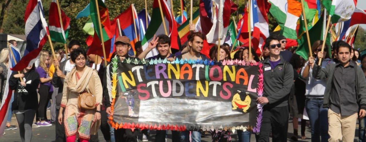 Students walk in the homecoming parade with sign saying 