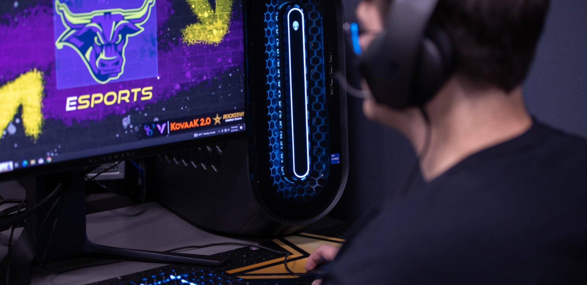 Student wearing headphones has the Maverick Esports logo pulled up on his gaming setup.