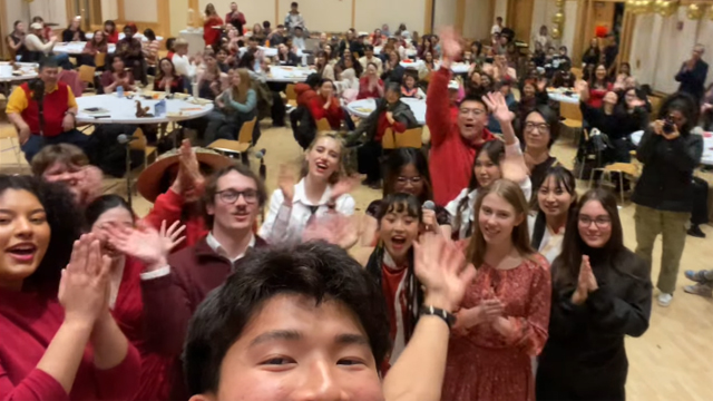 A crowd of people take a selfie in the Reid Ballroom, many of them are wearing red