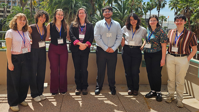A group of sociology students and their professor stand outdoors with palm trees in the background.