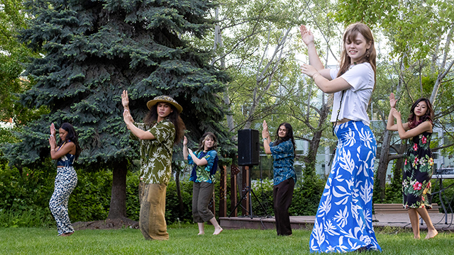 A group of students in similar poses, dancing on the Reid Campus Center side lawn