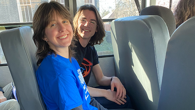 Amber Bakken (left) and Sebastian Wiedenhoeft seated next to each other on a bus