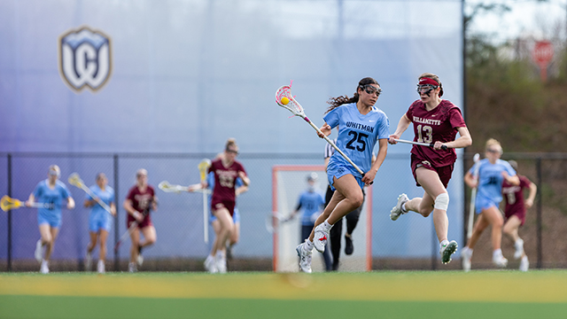 A Whitman lacrosse player with the number “25” on their jersey, leads a charge across the field