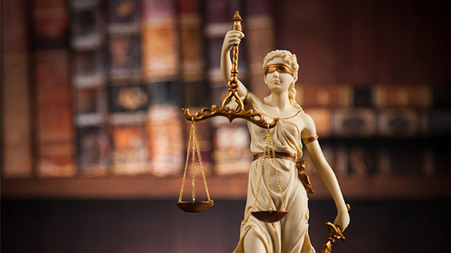 A figurine depicting Lady Justice, blindfolded, holding scales in one hand and a sword in the other