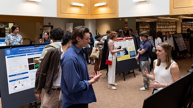 Students talk to passersby about their posters on display in Penrose Library