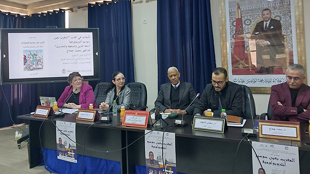 Lauren Osborne sits in a panel with four other presenters; all signage in the image is in Arabic