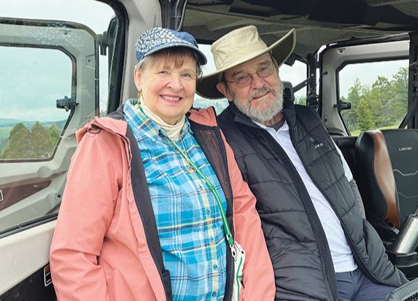 Janet Green Hunter stands next to the open door of a vehicle where Richard Hunter is seated 