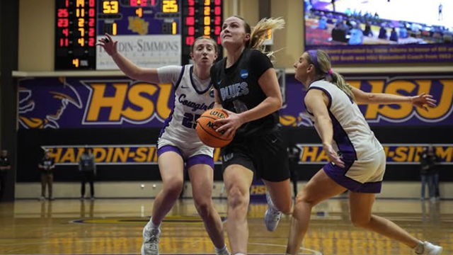 A Whitman women’s basketball player flanked by two opponents on the court