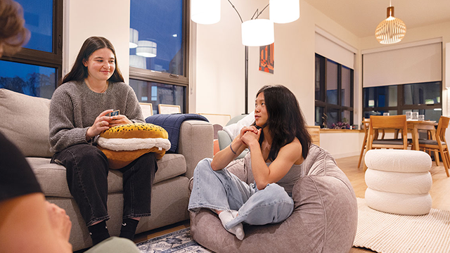 Students play a card game sitting in their Nancy Serrurier Village apartment