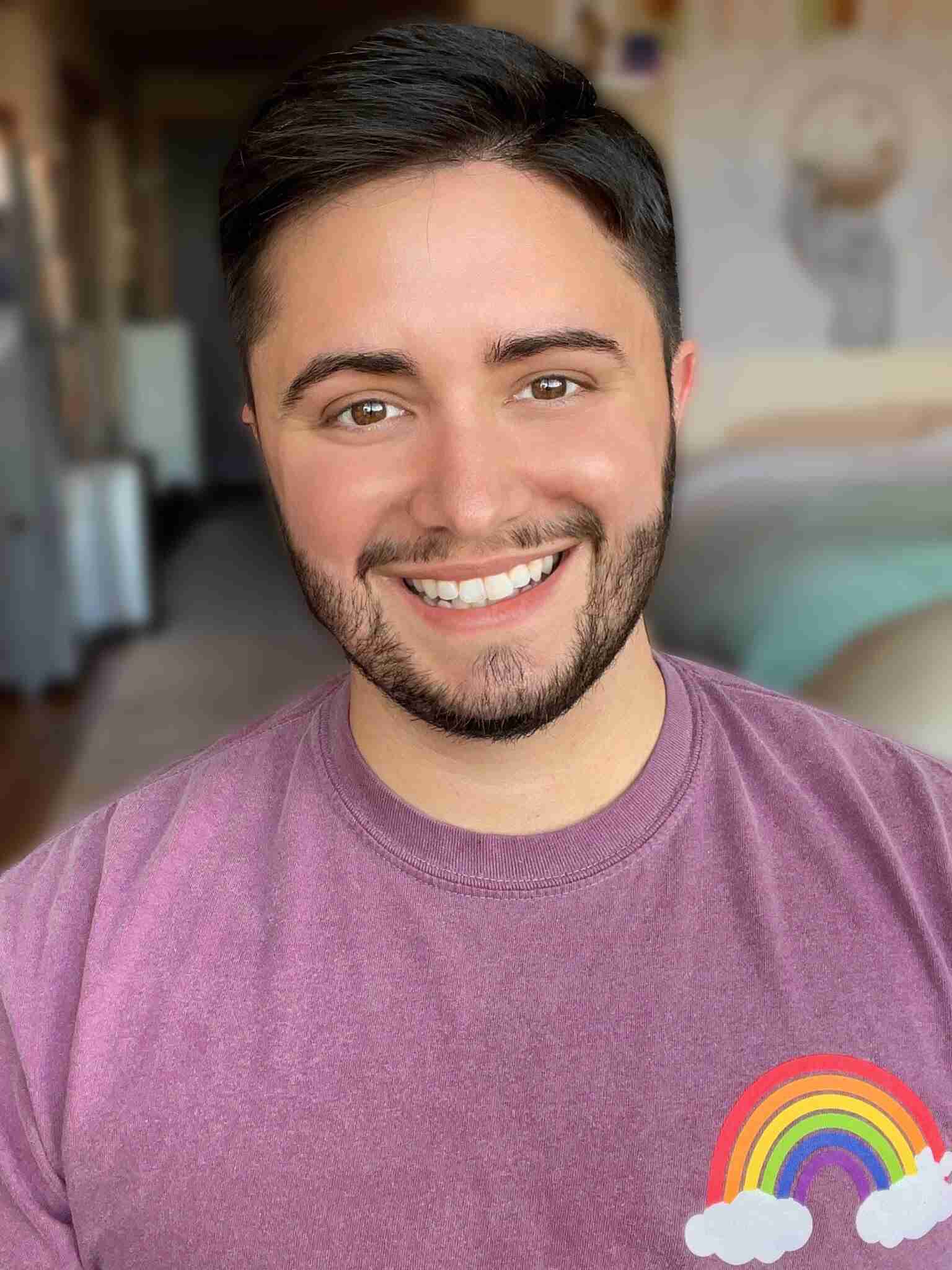 portrait of Aiden Thomas wearing a purple t-shirt with a rainbow design