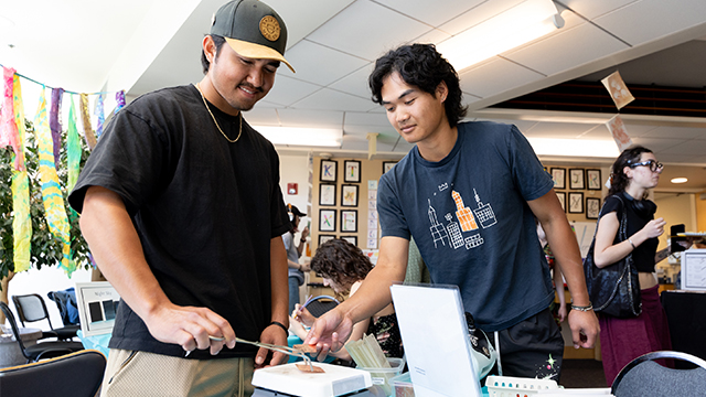 Two students interact with an object on a table at the Chemistry in Art display in the Hall of Science