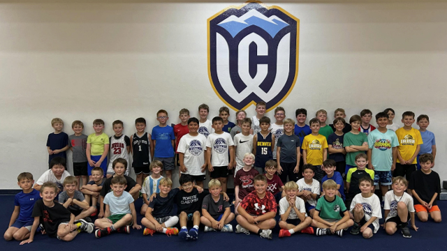 A large group of children pose for a photo in front of a large Whitman Athletics logo