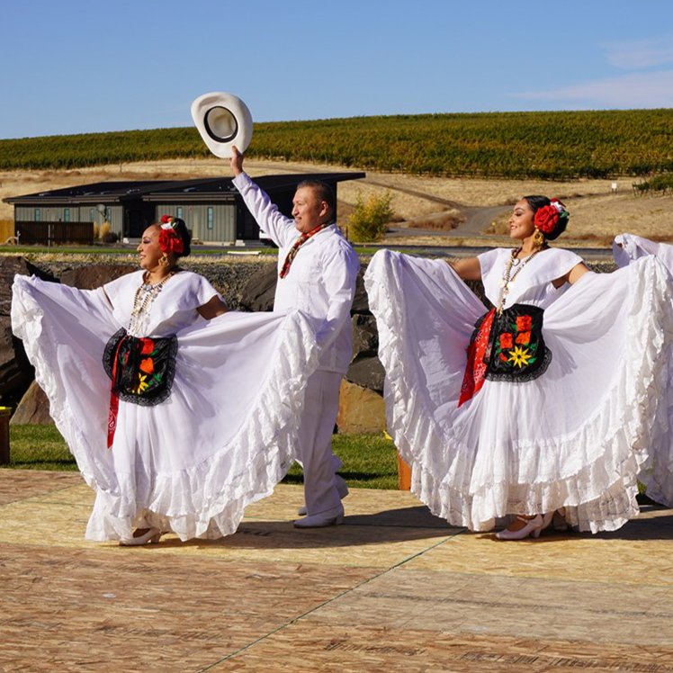 Dancers in traditional Mexican attire perform on an outdoor stage