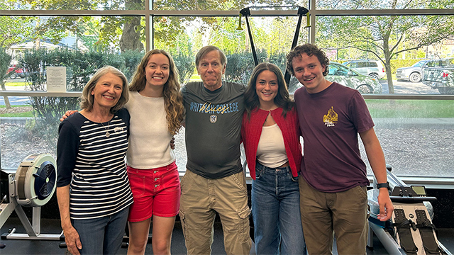 Pat Keef stands by a rowing machine with his wife and three students