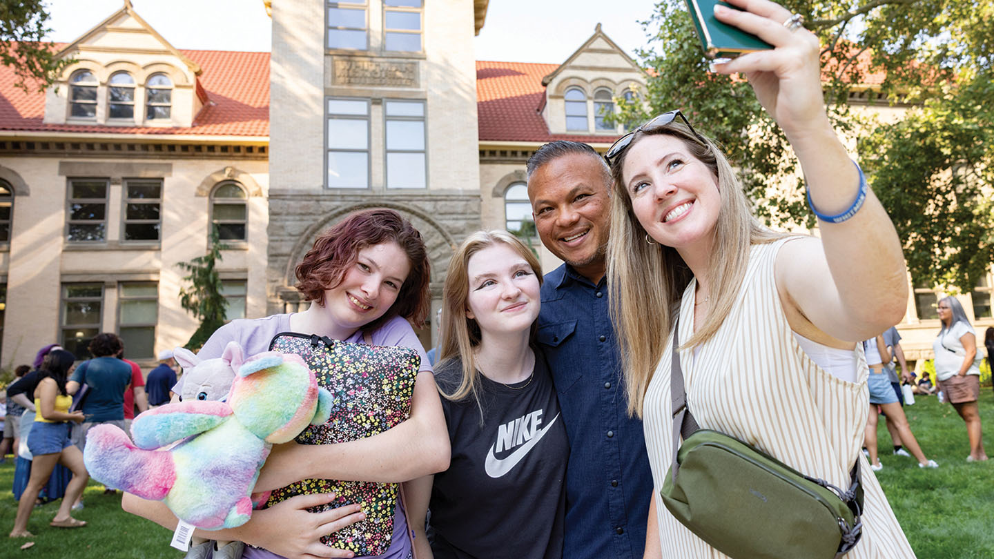 A family takes a selfie on the lawn in front of Whitman College's Memorial Building on move-in day.
