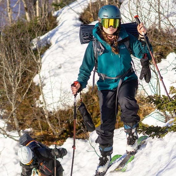 Hanna Grinstead climbs a snowy hillside in a helmet ski gear 