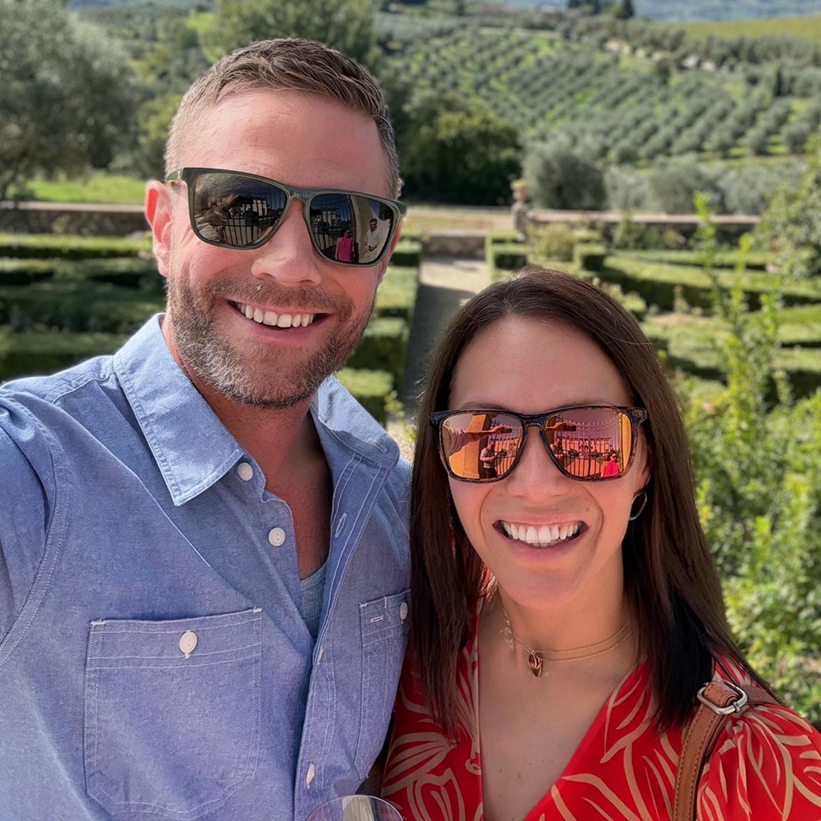 Tom and Alaina wearing sunglasses with vineyards in the background
