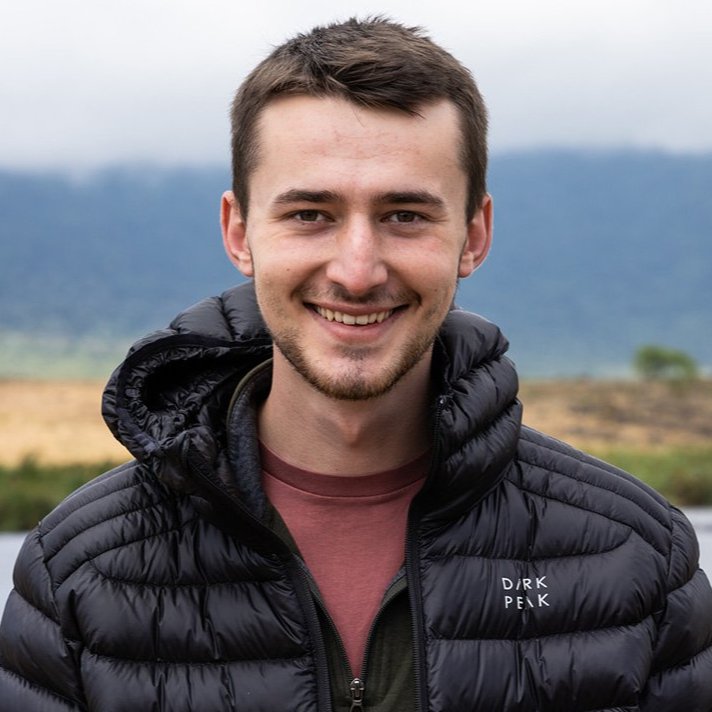 Fraser Moore in a dark parka standing by a body of water