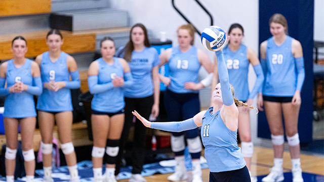 A Whitman volleyball player hits the ball while teammates watch from the sidelines