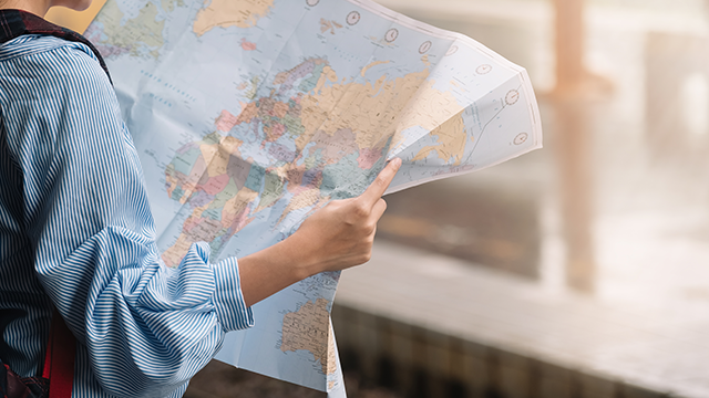 A person holding and looking at a physical map of the world