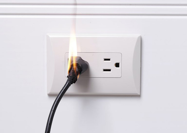 Black cord on fire plugged into white wall outlet.