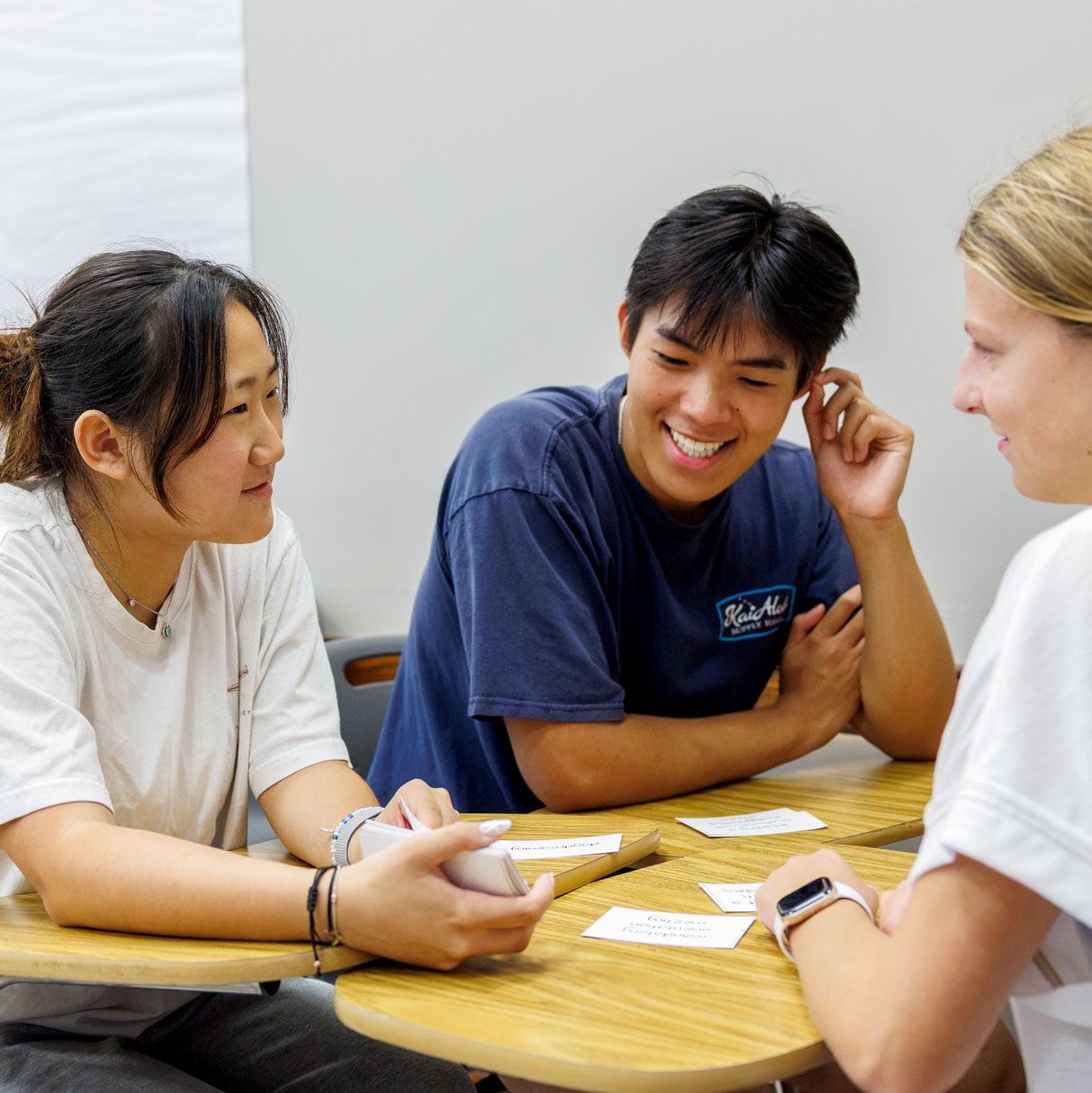 Three students sit at a table with paper in front of them