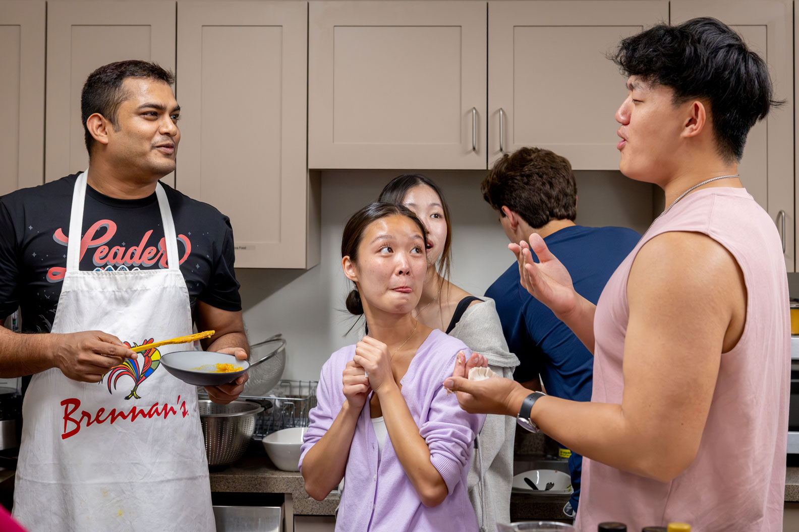 A doctoral student in an apron offers a dish to students as part of their first-year seminar Food, Identity, and the Art of Belonging  