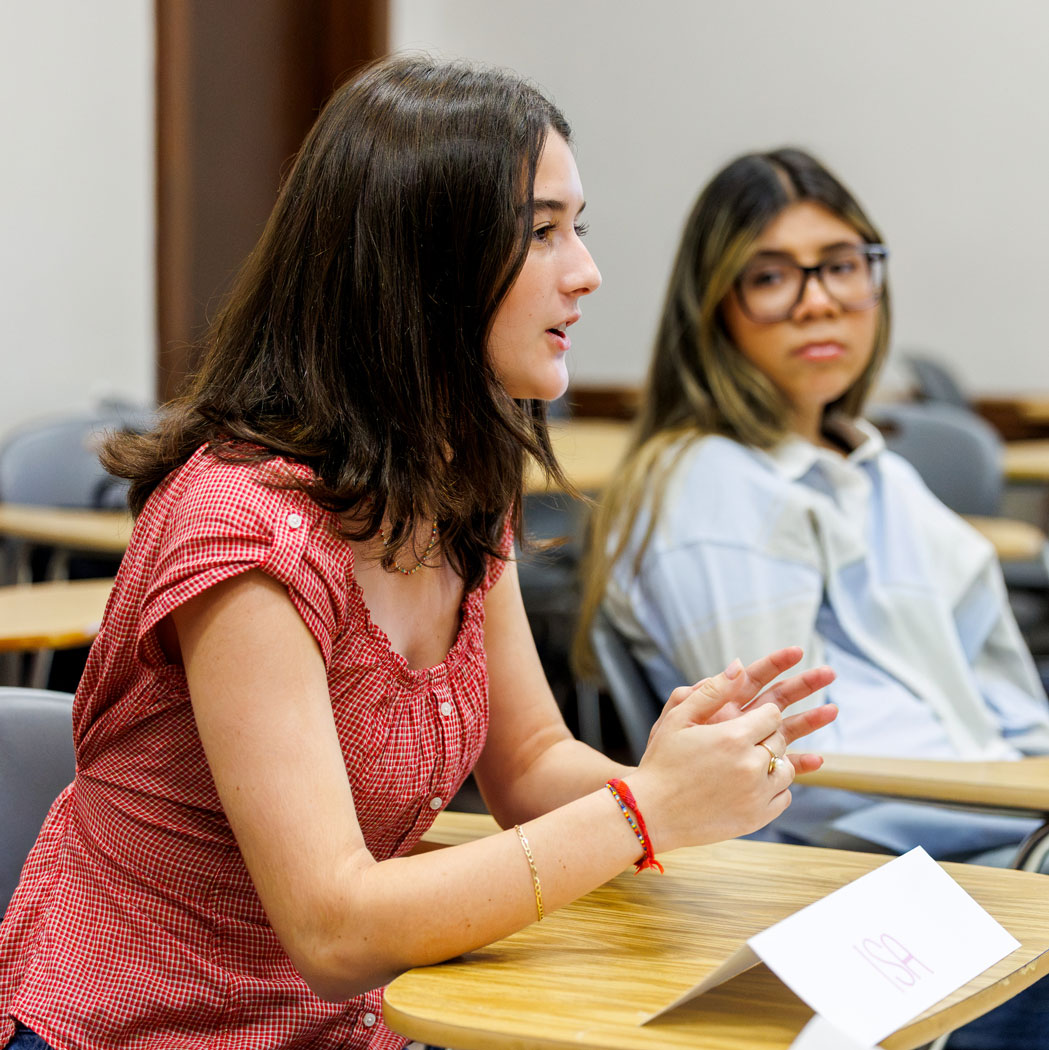 A student speaks in class while another student looks on