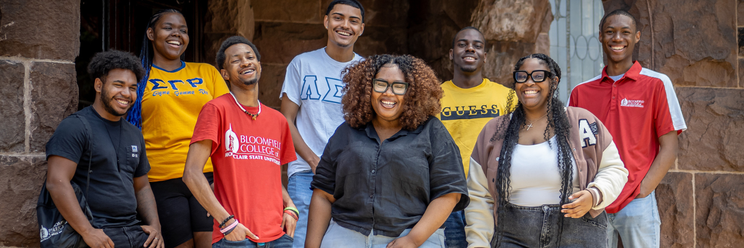 Group of students wearing Bloomfield College shirts taking a group photo on campus.