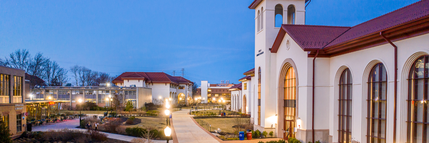 An evening view of Montclair State University's campus with illuminated buildings under a twilight sky.