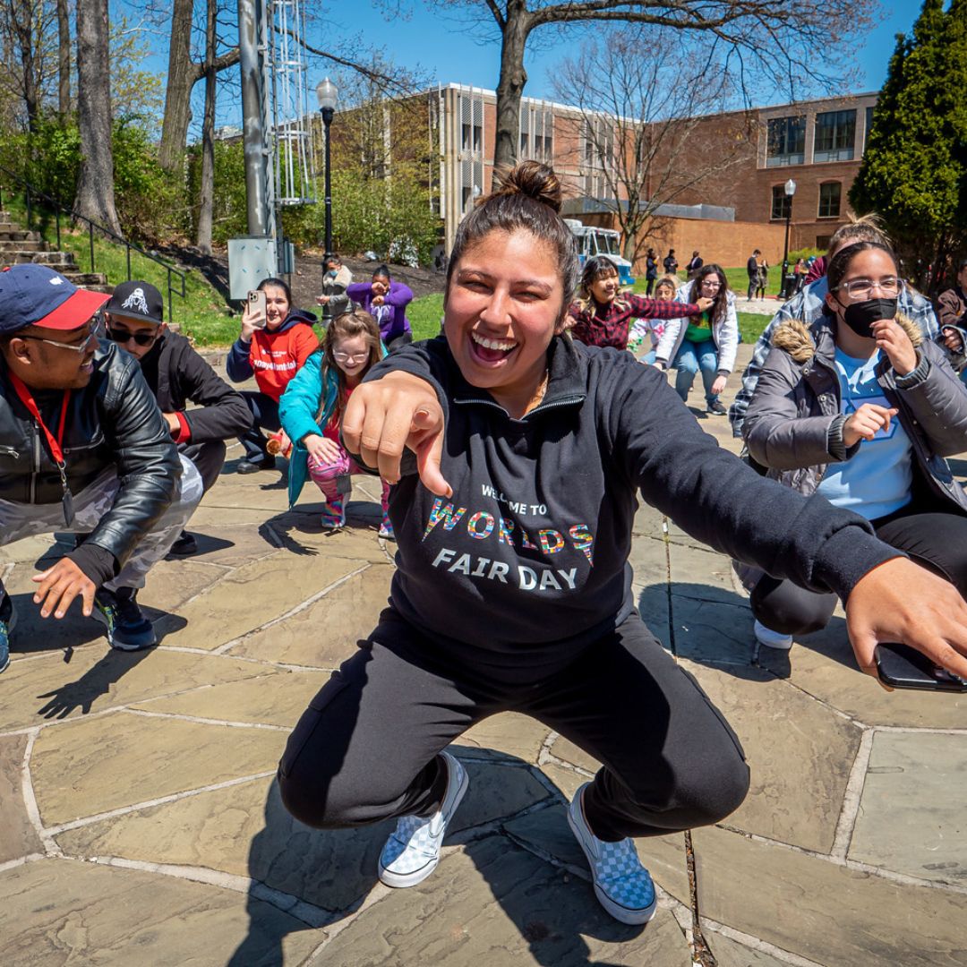 Student performers smiling and pointing to the camera during Worlds Fair Day.