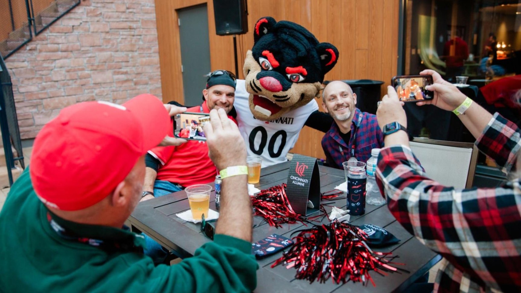 Alum posing with Bearcat Mascot at a Bearcats on the Road event