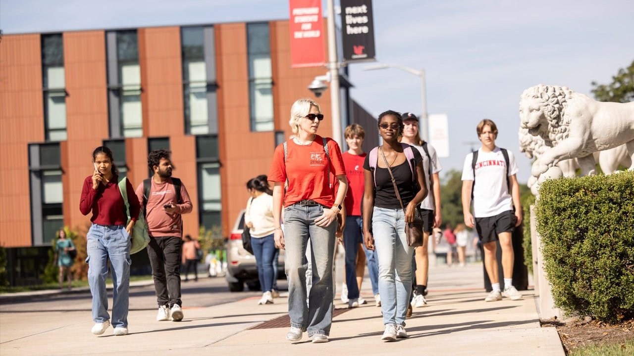 Group of several students walking on UC's campus.